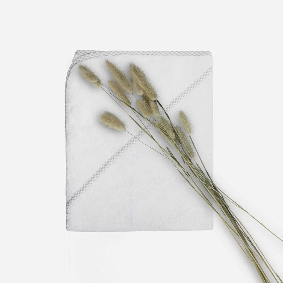 Cape de bain blanche à liseré vichy gris Comptoir du Bambou avec pampa Sortie de bain pliée pour bébé en éponge blanche avec liseré vichy gris et fleurs de pampa collection le petit bambou