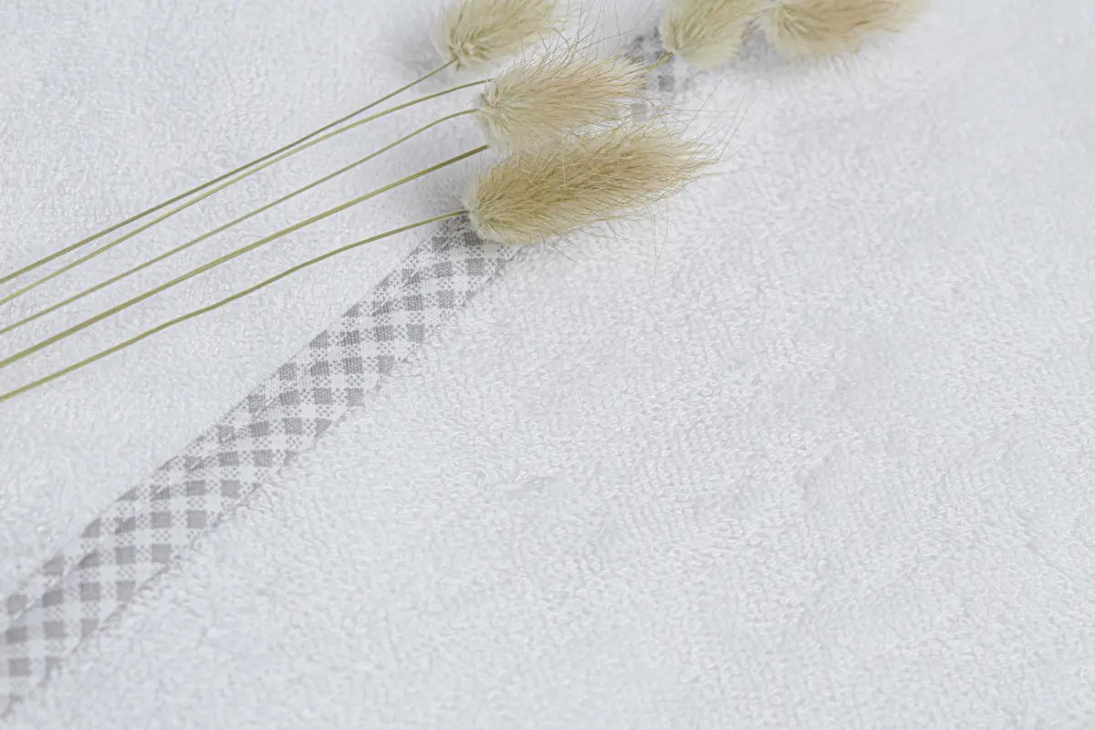 Détail cape de bain bébé blanche liseré vichy gris Comptoir du Bambou pampa Détail sortie de bain en éponge pour bébé blanche avec un liseré en vichy gris avec des fleurs de pampa