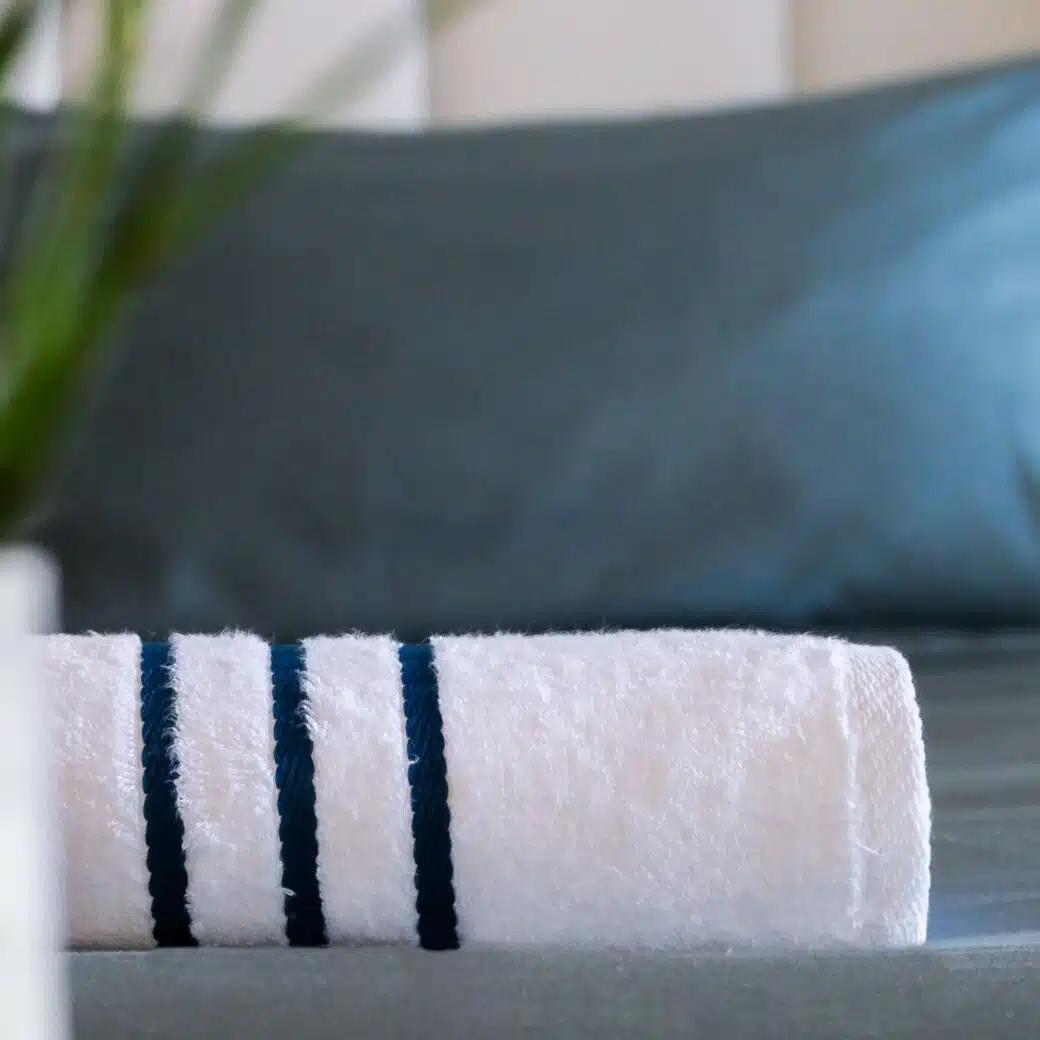 Serviettes en bambou haut de gamme, prêtes à offrir douceur et confort, méticuleusement disposées sur le lit d'une chambre d'hôtel, pour une expérience de séjour des plus agréables.