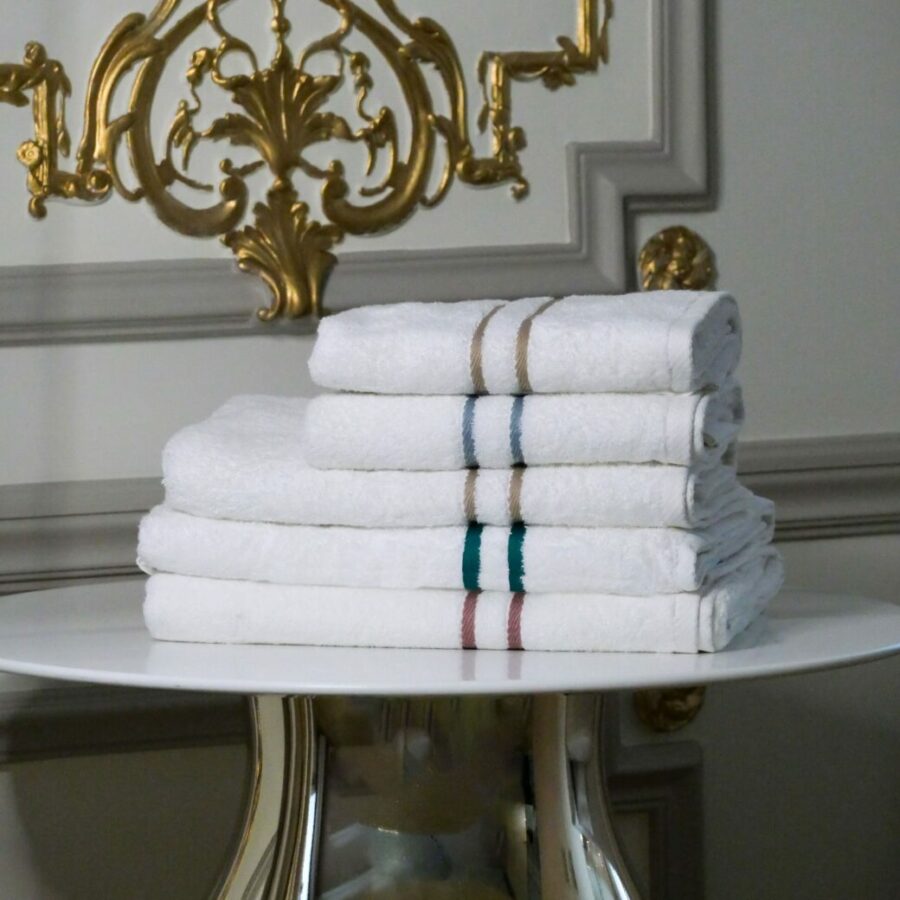 Plusieurs serviettes en bambou finement pliées, disposées sur une table dans un appartement haussmannien de luxe, ajoutant une touche de confort et d'élégance à cet espace prestigieux.