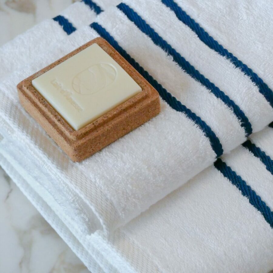 Serviette en bambou de luxe artistiquement agencée sur un support en marbre accompagner d'un savon aux huiles essentielles naturelles, accentuant le décor sophistiqué d'une salle de bain contemporaine