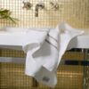 Image d'une serviette en bambou de qualité supérieure déposée avec finesse sur le bord d'un lavabo en marbre dans une salle de bain raffinée.