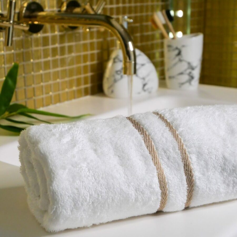 Vue détaillée d'une serviette en bambou moelleuse et luxueuse posée avec élégance sur le bord d'une baignoire en céramique dans une salle de bain contemporaine.