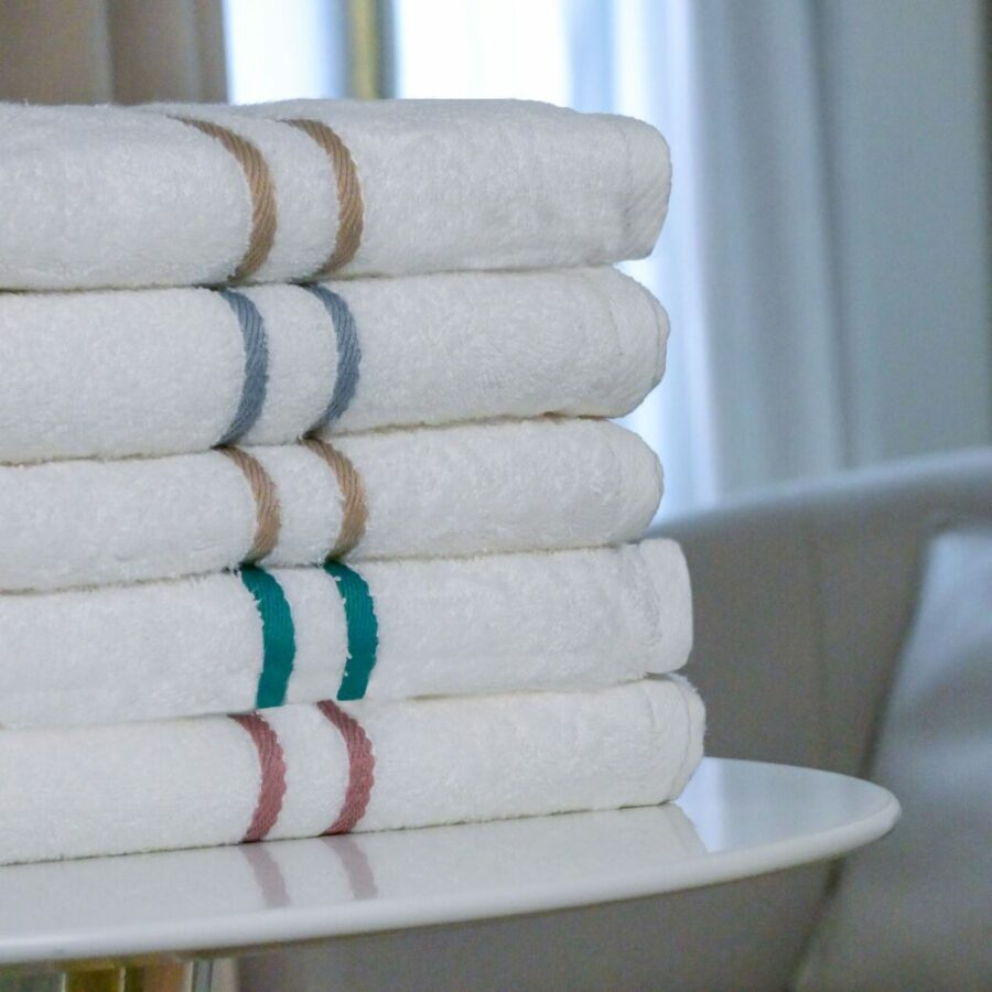 Pille de serviettes en fibre de bambou moelleuses drapées élégamment sur une table d'hotel de luxe, complétant l'esthétique sophistiquée de cette salle de bain moderne.