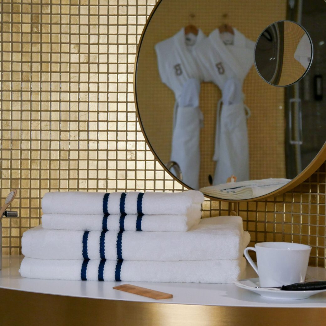 Serviettes en bambou d'une grande douceur et pliées avec élégance, soigneusement disposées sur une table de maquillage, ajoutant une touche de raffinement et de confort à la décoration haut de gamme de cette magnifique salle de bain. Dans le reflet du miroir, les peignoirs en bambou augmentent le bien-être et le lifestyle de cette pièce.