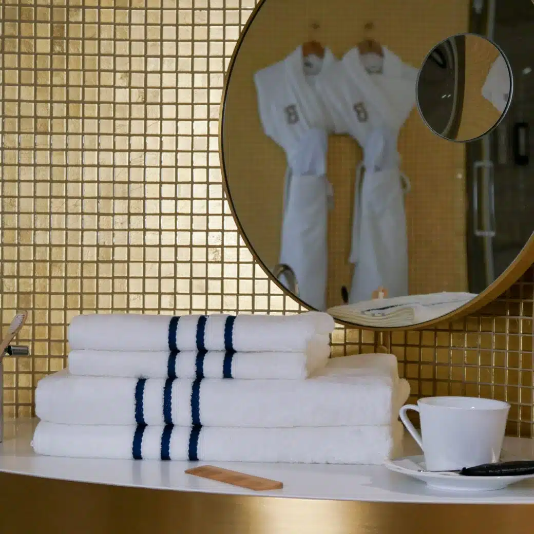 Serviettes en bambou d'une grande douceur et pliées avec élégance, soigneusement disposées sur une table de maquillage, ajoutant une touche de raffinement et de confort à la décoration haut de gamme de cette magnifique salle de bain. Dans le reflet du miroir, les peignoirs en bambou augmentent le bien-être et le lifestyle de cette pièce.