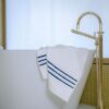 Serviette en tissu de bambou délicatement pliée sur le bord d'une baignoire pour une pause relaxante et luxueuse dans cette salle de bain apaisante.