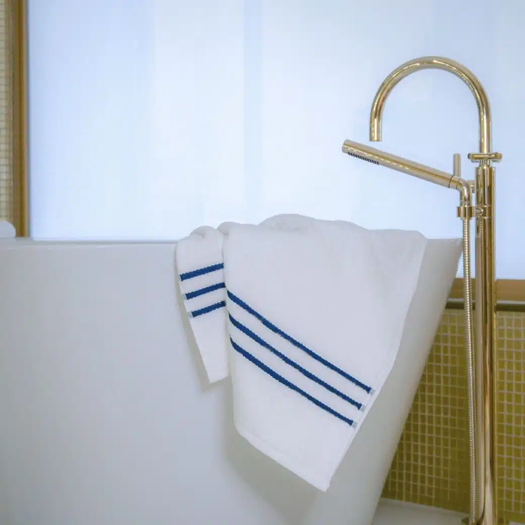 Serviette en tissu de bambou délicatement pliée sur le bord d'une baignoire pour une pause relaxante et luxueuse dans cette salle de bain apaisante.